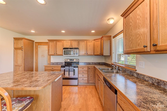 kitchen featuring appliances with stainless steel finishes, a sink, light wood-style floors, recessed lighting, and brown cabinetry