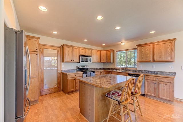 kitchen featuring appliances with stainless steel finishes, a sink, recessed lighting, light wood-style flooring, and a kitchen island