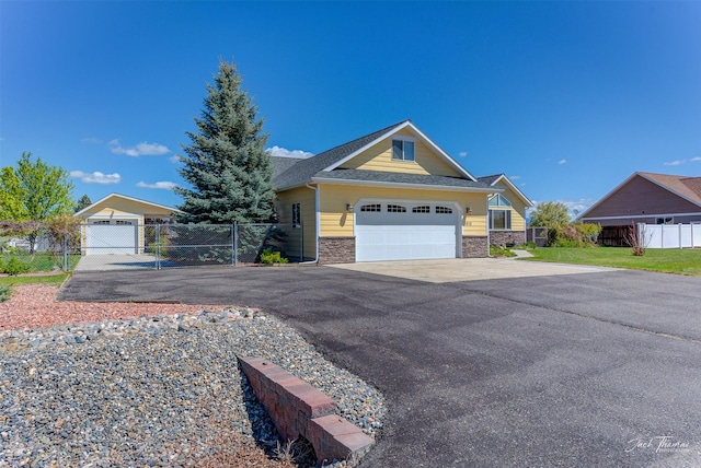 view of front facade featuring a garage, stone siding, a shingled roof, driveway, and a gate