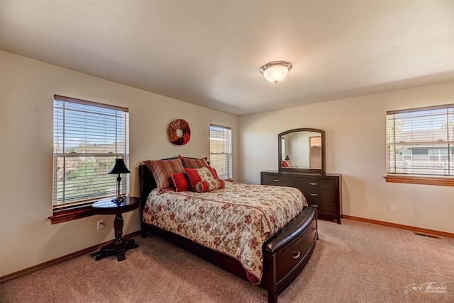 bedroom with light colored carpet, multiple windows, and baseboards