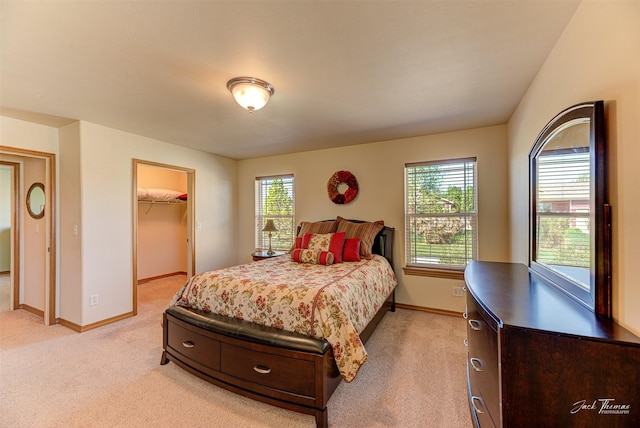 bedroom with light carpet, baseboards, and a spacious closet