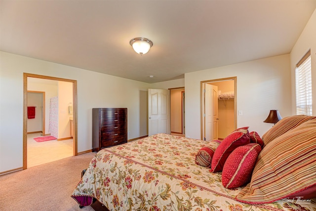 carpeted bedroom featuring a walk in closet, baseboards, and ensuite bath