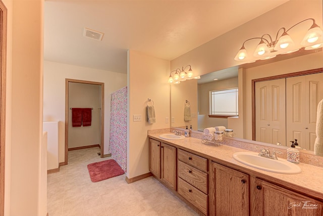 full bath featuring double vanity and baseboards