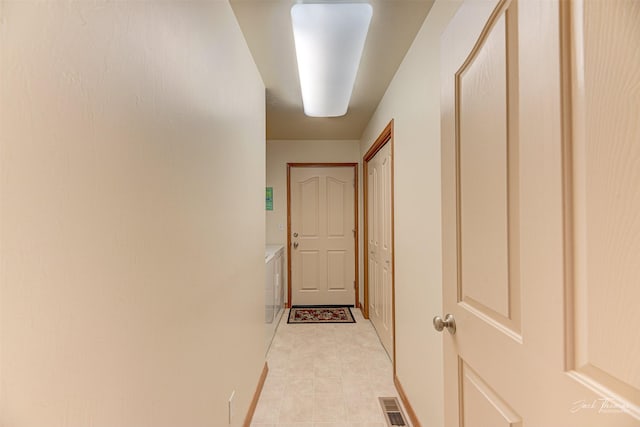 corridor featuring baseboards and washing machine and dryer