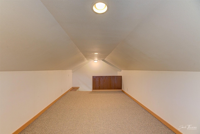 bonus room with light colored carpet, vaulted ceiling, and baseboards