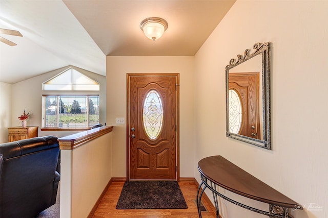 foyer featuring wood finished floors, a ceiling fan, baseboards, and vaulted ceiling