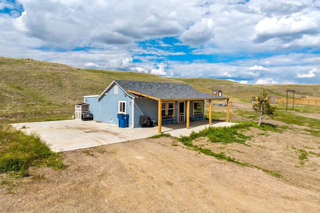 49 Embry Ln, Great Falls, MT 59404 - back of house with dirt driveway, a mountain view, and a porch