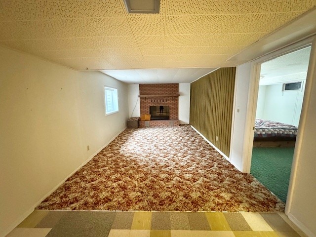 unfurnished living room featuring carpet floors, a fireplace, and baseboards