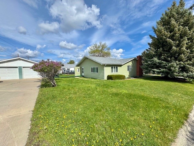 view of side of property featuring a lawn, an outdoor structure, and a detached garage