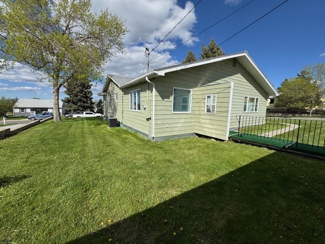 view of side of home featuring a lawn and central AC