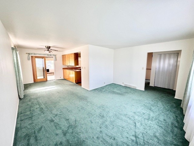 unfurnished living room featuring dark carpet and a ceiling fan