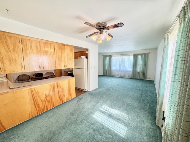 kitchen with freestanding refrigerator, ceiling fan, carpet, and light countertops