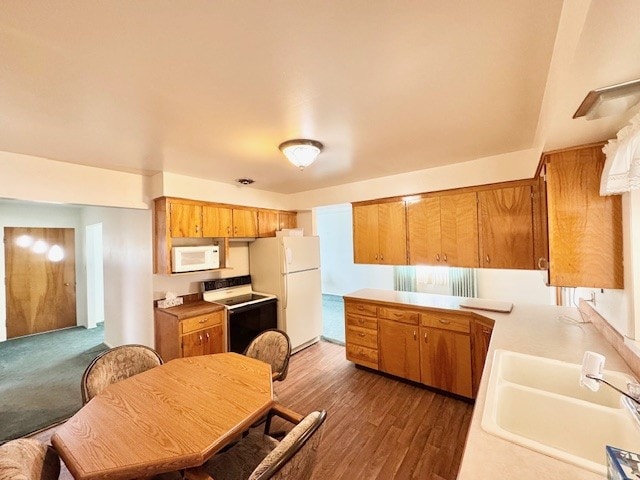 kitchen with white appliances, a sink, light countertops, brown cabinetry, and wood finished floors