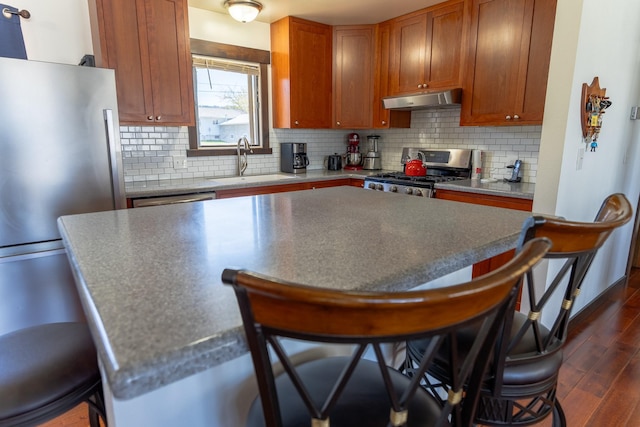 1827 Hollins Ave, Helena, MT 59601 - kitchen with stainless steel appliances, a sink, under cabinet range hood, a breakfast bar area, and dark wood finished floors