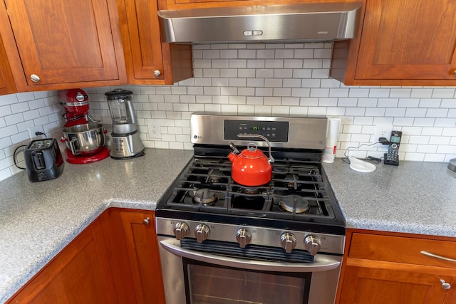 1827 Hollins Ave, Helena, MT 59601 - kitchen with gas range, range hood, brown cabinetry, and decorative backsplash