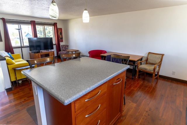 1827 Hollins Ave, Helena, MT 59601 - kitchen featuring dark wood-style floors, a kitchen island, a textured ceiling, brown cabinets, and baseboards