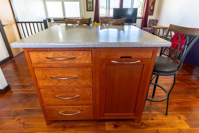 1827 Hollins Ave, Helena, MT 59601 - kitchen featuring a center island, brown cabinetry, dark wood-type flooring, a breakfast bar, and light countertops