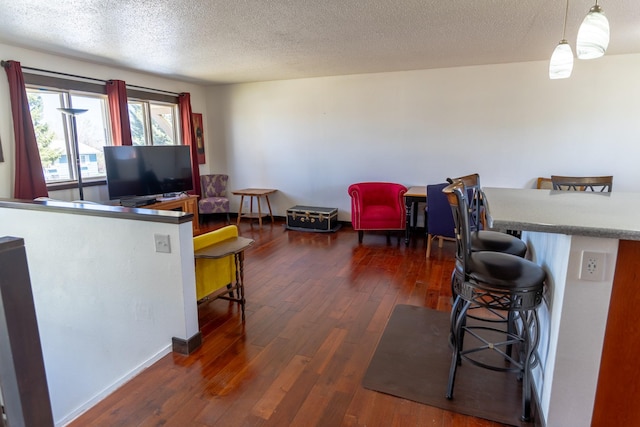 1827 Hollins Ave, Helena, MT 59601 - kitchen with a breakfast bar area, dark wood-style floors, a textured ceiling, hanging light fixtures, and baseboards