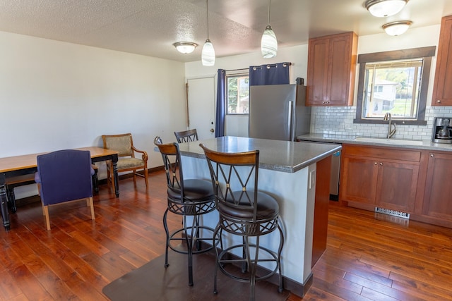 1827 Hollins Ave, Helena, MT 59601 - kitchen featuring a sink, appliances with stainless steel finishes, a breakfast bar, dark wood-style flooring, and brown cabinetry
