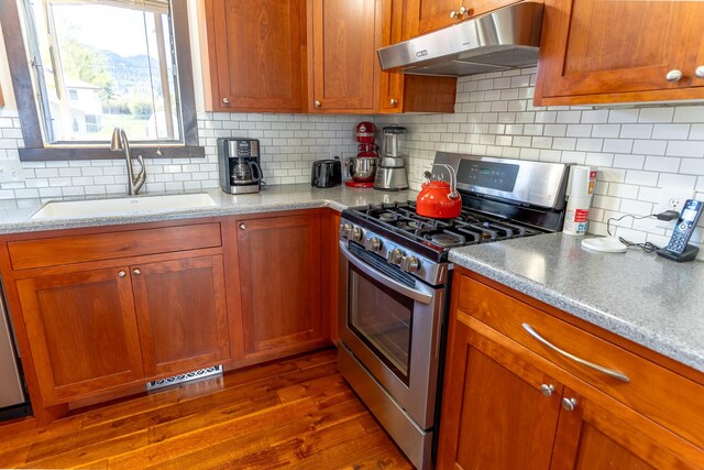 1827 Hollins Ave, Helena, MT 59601 - kitchen featuring stainless steel range with gas stovetop, under cabinet range hood, a sink, tasteful backsplash, and dark wood finished floors