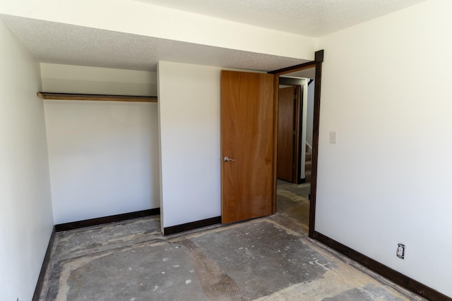 1827 Hollins Ave, Helena, MT 59601 - unfurnished bedroom featuring concrete flooring, baseboards, a textured ceiling, and a closet