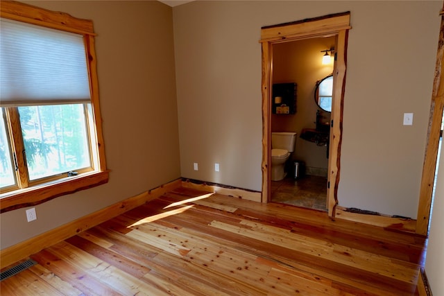 237 N Monture Ct, Seeley Lake, MT 59868 - unfurnished bedroom with light wood-style flooring, baseboards, and connected bathroom