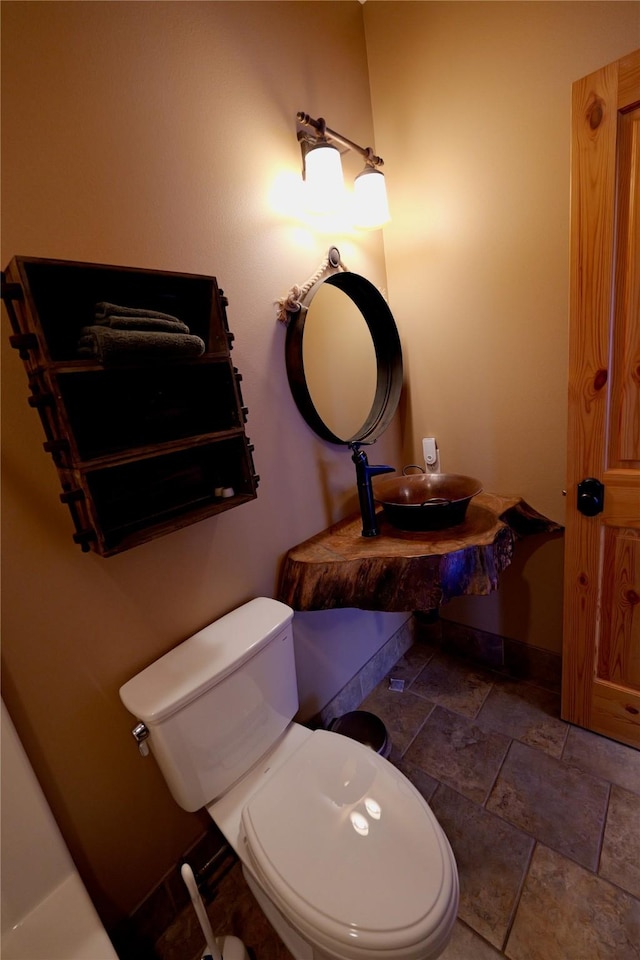 237 N Monture Ct, Seeley Lake, MT 59868 - half bathroom featuring a sink, stone finish floors, toilet, and baseboards
