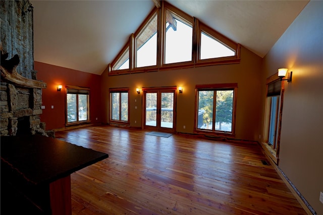 237 N Monture Ct, Seeley Lake, MT 59868 - unfurnished living room with high vaulted ceiling, wood-type flooring, and a stone fireplace