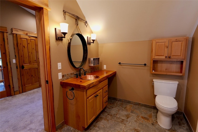 237 N Monture Ct, Seeley Lake, MT 59868 - bathroom featuring lofted ceiling, baseboards, toilet, and vanity