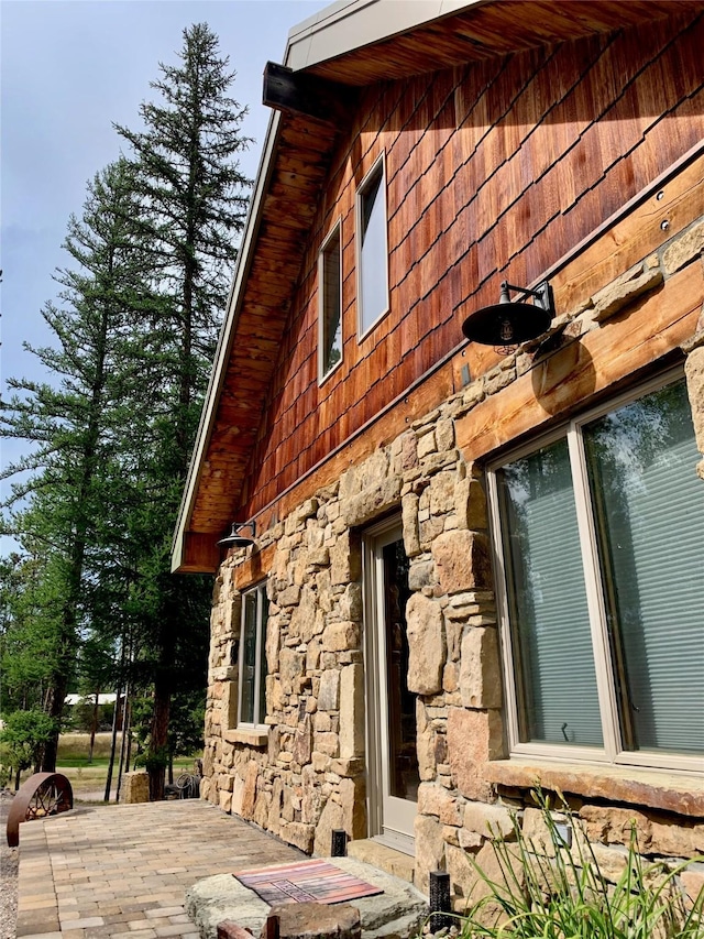 237 N Monture Ct, Seeley Lake, MT 59868 - view of property exterior featuring stone siding and a patio area