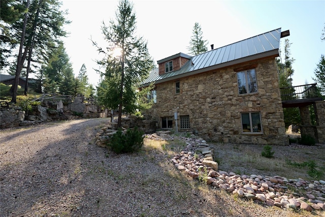 237 N Monture Ct, Seeley Lake, MT 59868 - view of side of property with stone siding, a metal roof, and a balcony