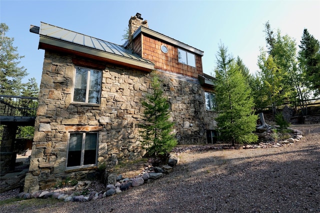 237 N Monture Ct, Seeley Lake, MT 59868 - view of property exterior featuring a standing seam roof, stone siding, a chimney, and metal roof