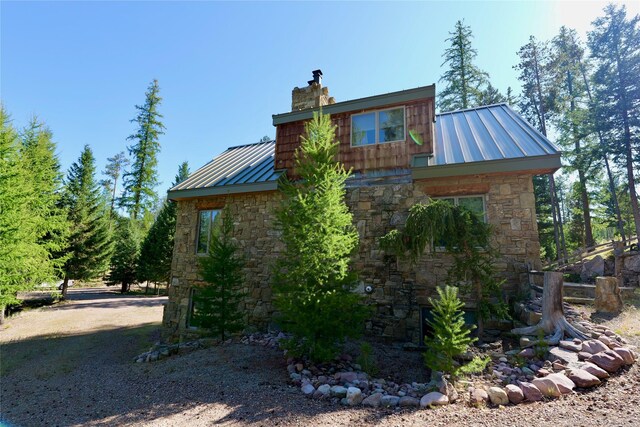 237 N Monture Ct, Seeley Lake, MT 59868 - view of side of property with stone siding, a standing seam roof, a metal roof, and a chimney