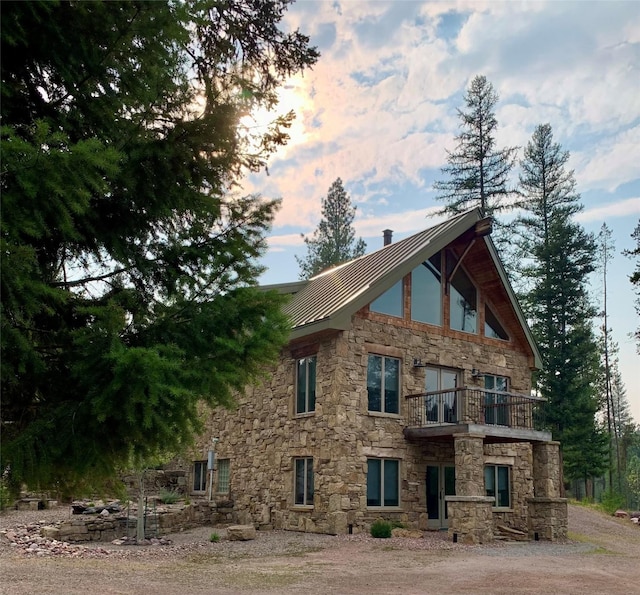 237 N Monture Ct, Seeley Lake, MT 59868 - view of side of home featuring stone siding, a balcony, metal roof, and a standing seam roof