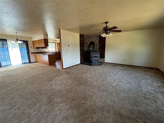 5061 Falcon Ln, Stevensville, MT 59870 - unfurnished living room with a wood stove, a textured ceiling, carpet floors, ceiling fan, and baseboards