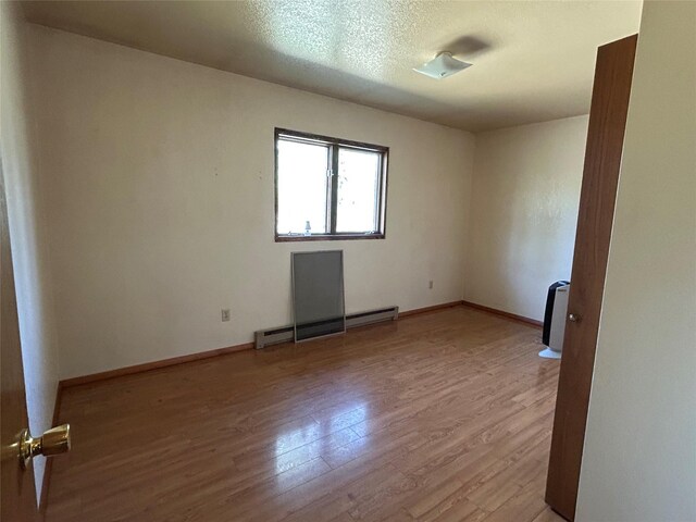 5061 Falcon Ln, Stevensville, MT 59870 - unfurnished room with wood finished floors, a baseboard heating unit, baseboards, and a textured ceiling
