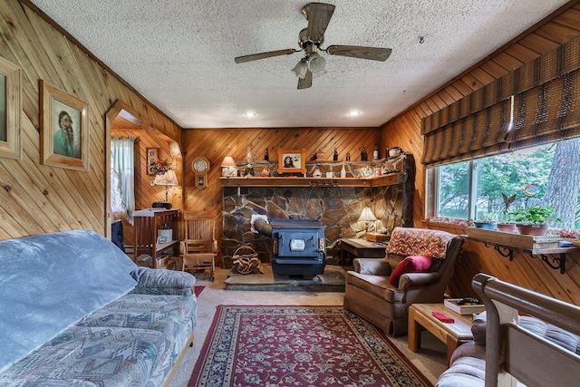 521 Clay St, Thompson Falls, MT 59873 - living room with a wood stove, wooden walls, a textured ceiling, a ceiling fan, and carpet
