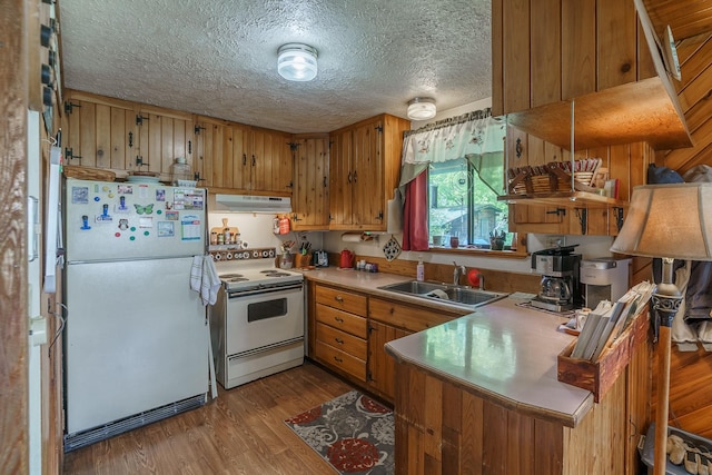 521 Clay St, Thompson Falls, MT 59873 - kitchen featuring white appliances, a sink, under cabinet range hood, brown cabinetry, and wood finished floors