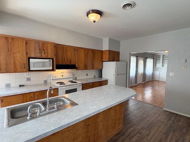 330 N Walnut St, Dillon, MT 59725 - kitchen with white appliances, under cabinet range hood, brown cabinets, and a sink