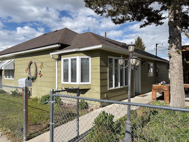 330 N Walnut St, Dillon, MT 59725 - view of home's exterior featuring a fenced front yard and roof with shingles