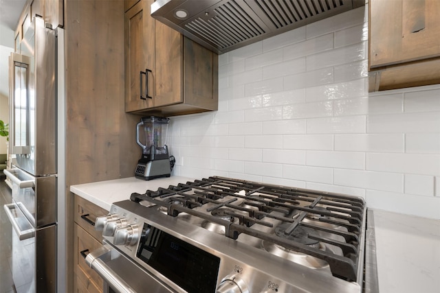 322 Hemlock St, Anaconda, MT 59711 - kitchen view of stainless steel appliances, decorative backsplash, custom range hood, and brown cabinetry