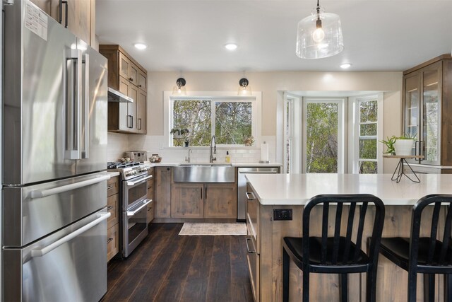 322 Hemlock St, Anaconda, MT 59711 - kitchen featuring stainless steel appliances, a sink, light countertops, dark wood-style floors, and a kitchen breakfast bar