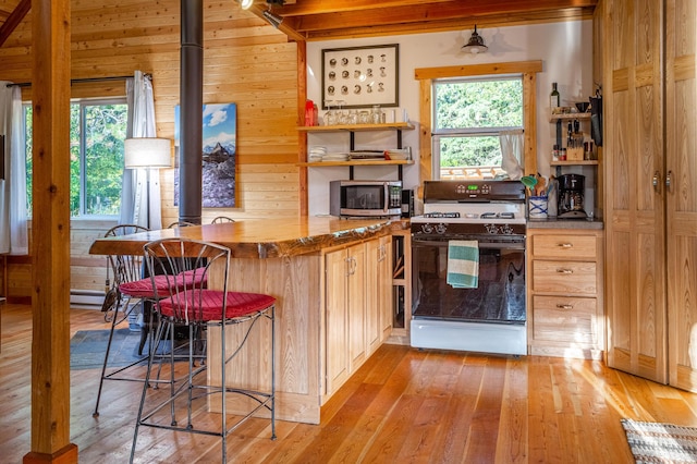 155 Seville Ln, Coram, MT 59913 - kitchen with gas stove, light wood-type flooring, stainless steel microwave, wood walls, and open shelves