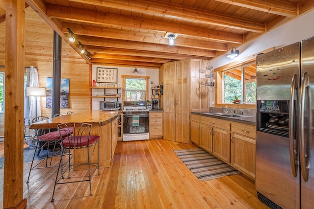 155 Seville Ln, Coram, MT 59913 - kitchen featuring appliances with stainless steel finishes, a sink, wood ceiling with exposed beams, plenty of natural light, and a kitchen bar