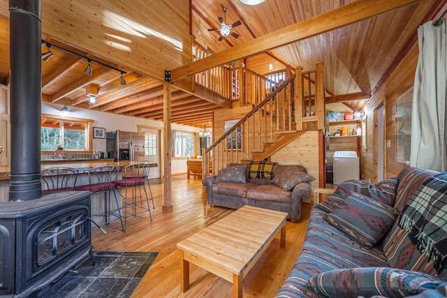 155 Seville Ln, Coram, MT 59913 - living area with wooden ceiling, a wood stove, stairway, wood walls, and light wood-style flooring