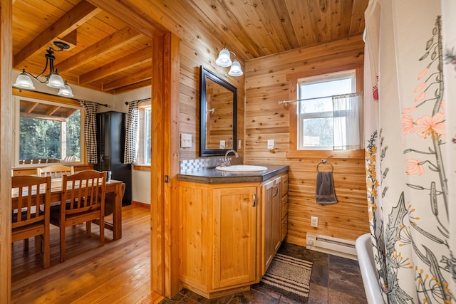 155 Seville Ln, Coram, MT 59913 - bathroom featuring wood ceiling with exposed beams, a baseboard radiator, wood walls, healthy amount of natural light, and vanity