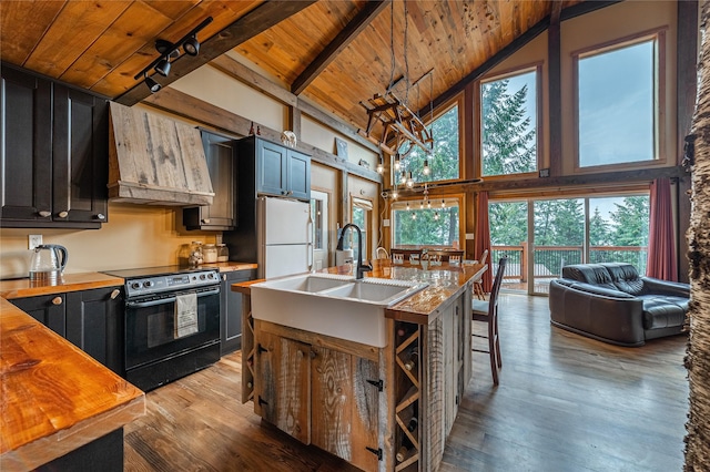 277 Ridge Loop Rd, Rexford, MT 59930 - kitchen featuring black range with electric stovetop, wooden ceiling with exposed beams, premium range hood, high vaulted ceiling, and freestanding refrigerator