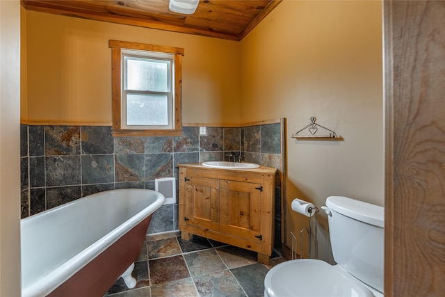 277 Ridge Loop Rd, Rexford, MT 59930 - bathroom featuring wood ceiling, tile walls, toilet, a freestanding tub, and stone tile flooring