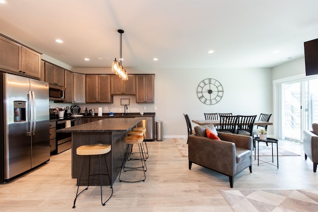 4394 Brookside Ln, Bozeman, MT 59718 - kitchen featuring appliances with stainless steel finishes, dark countertops, recessed lighting, a kitchen island, and a kitchen breakfast bar