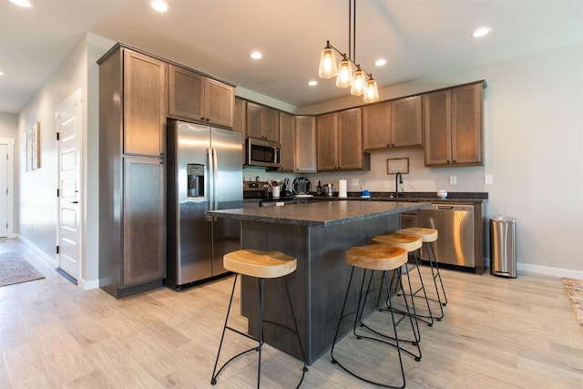 4394 Brookside Ln, Bozeman, MT 59718 - kitchen with appliances with stainless steel finishes, dark countertops, baseboards, light wood-style floors, and a kitchen bar